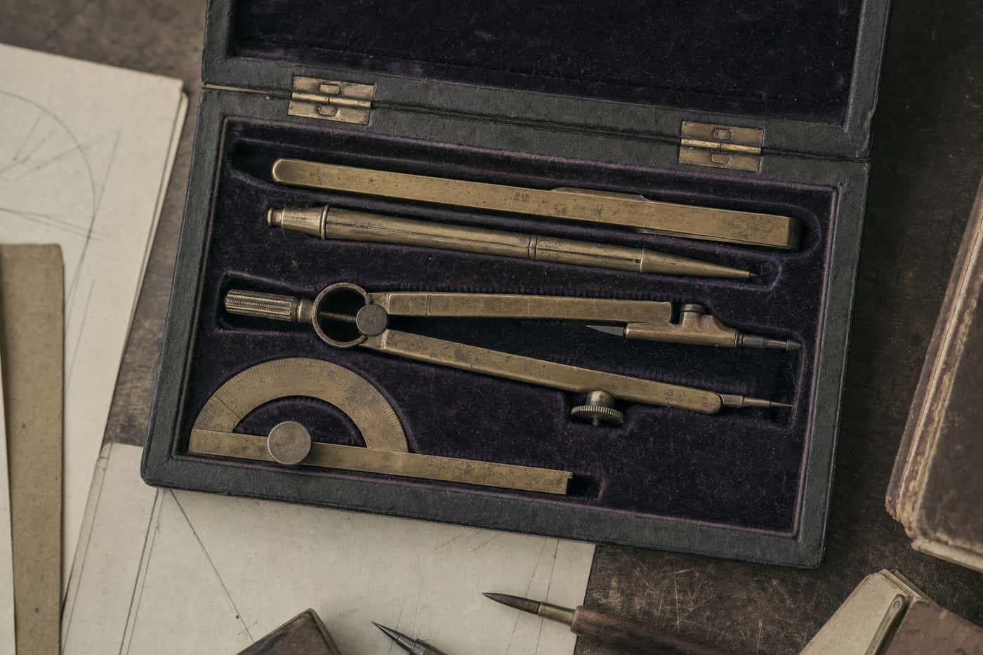 A fitted case of brass drawing instruments: dividers, compass, ruling pen and protractor.