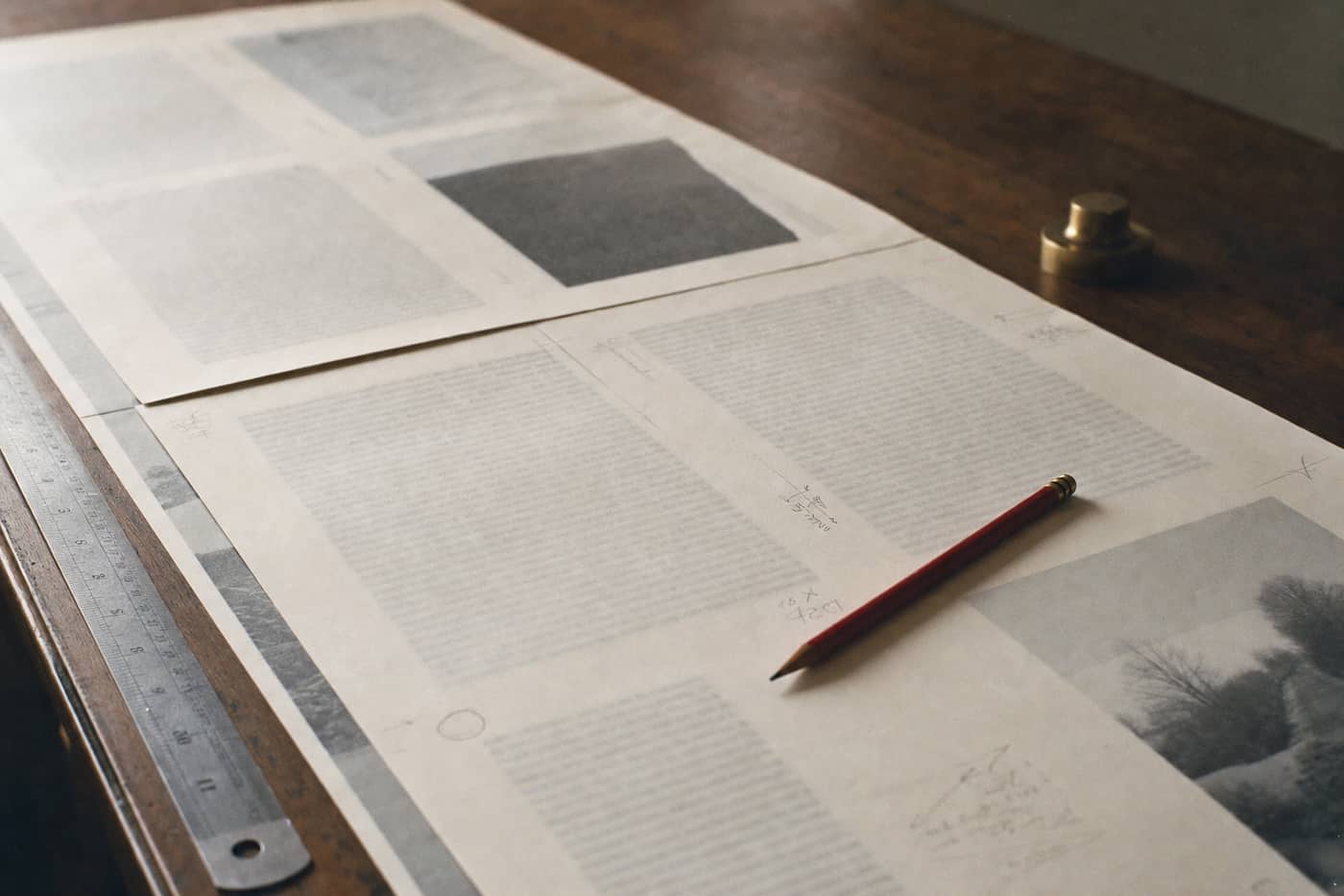 Printed galley proofs across a desk with a red editing pencil and margin marks.